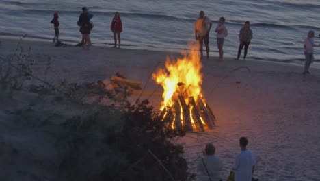 Menschenmassen-Beobachten-Bei-Sonnenuntergang-Brennende-Lagerfeuer-Am-Strand-Von-Lettland