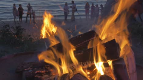 Menschen-Beobachten-Bei-Sonnenuntergang-Brennende-Lagerfeuer-Am-Strand-Von-Lettland