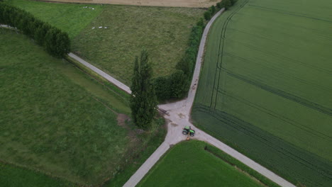 Drone-lowering-tilt-shot-off-a-tractor-mowing-a-field-on-a-cloudy-day-in-Belgium
