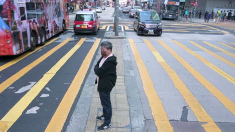 Un-Peatón-Espera-Que-Un-Semáforo-Se-Ponga-Verde-En-La-Acera-Entre-Caminos-En-Un-Cruce-De-Cebra-En-Hong-Kong