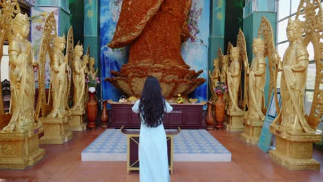 Mujer-Adora-Una-Estatua-Gigante-De-Buda-Laica-Hecha-De-Flores-Inmortales-En-La-Pagoda-Linh-Phuoc,-Da-Lat-City,-Vietnam