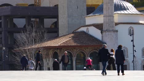 People-walking-in-front-of-mosque-on-main-square-of-Tirana-capital-city,-Albania
