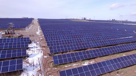 Rows-of-dark-solar-panels-at-Michigan-power-station,-rising-aerial-pan