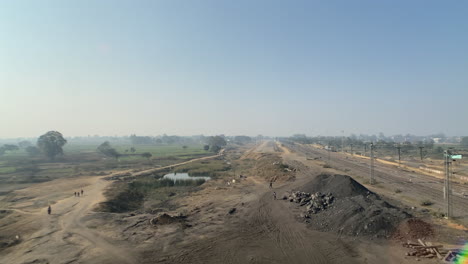 Long-shot-of-people-walking-near-coal-mountain,-rail-track