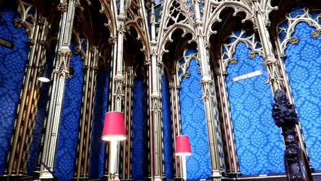 Panning-shot-of-blue-velvet-walls-with-red-lamps-in-Westminster-Abbey,-London
