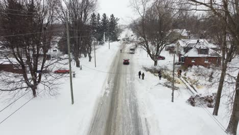 Aerial-drone-shot-of-residents-of-a-Toronto-neighborhood-clearing-a-fallen-tree-that-had-collapsed-onto-power-lines-after-a-heavy-snowstorm,-Ontario,-Canada