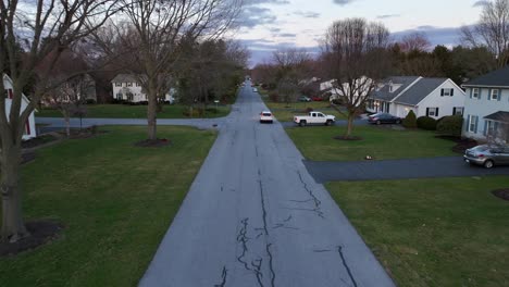 Aerial-tracking-shot-of-white-Honda-CRV-suv-driving-through-American-neighborhood-at-dusk-in-winter