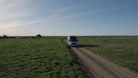 Tracking-backward-shot-of-a-camper-van-driving-off-road-locking-for-a-place-to-camp-in-the-south-of-Spain-at-sunset