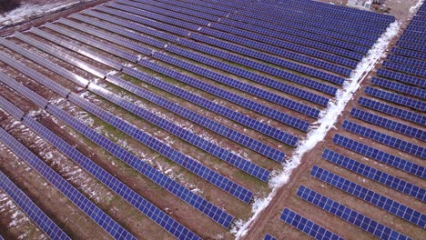 Rows-of-panels-at-huge-unrecognizable-solar-power-park,-aerial-pan