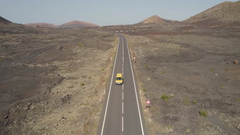 Aerial-view-on-top-of-a-highway-in-the-middle-a-dry-and-arid-volcanic-landscape-at-Lanzarote,-Canary-Islands-in-Spain
