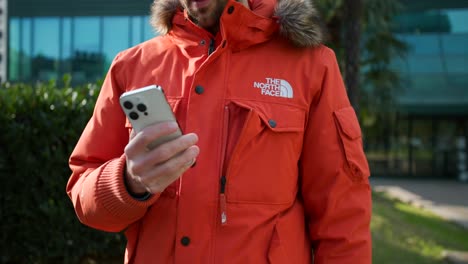 This-stock-footage-shows-a-man-taking-a-smartphone-from-the-pocket-in-his-jacket,-checking-texts,-and-then-placing-the-smartphone-back