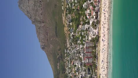 Beach-at-Camps-Bay-in-Cape-Town,-South-Africa---vertical-aerial-parallax