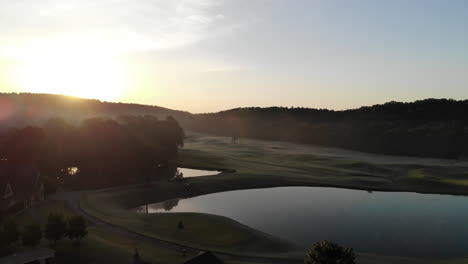 Sunrise-aerial-of-golf-course-greenway-with-lake-in-the-shot