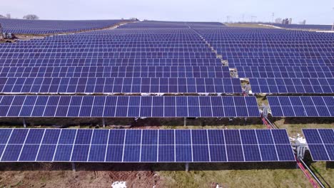 Rows-of-solar-panels-at-huge-power-farm-in-Michigan,-sideways-aerial