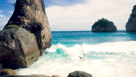 Pan-wide-landscape-shot-of-a-rocky-white-sand-tropical-beach-in-Bali,-Indonesia-during-a-sunny-clear-day