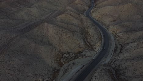 Aerial-Tilt-Up-Reveal-Sunset-On-Horizon-Over-RCD-Road-Through-Remote-Balochistan-Dramatic-Landscape
