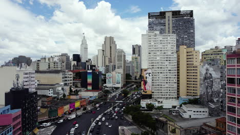 Drone-shot-rising-over-traffic-on-Avenida-Prestes-Maia-towards-skyscrapers-in-downtown-Sao-Paulo,-sunny-Brazil