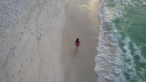 Mujer-De-Rosa-Caminando-Por-La-Playa-De-Aguas-Esmeraldas-De-Arena-Blanca-Del-Golfo-De-México-En-Pensacola,-Florida
