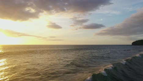 Luftaufnahme-Mit-Der-Sonne,-Die-Sich-Bei-Sonnenuntergang-In-Einem-Atemberaubenden-Strandbereich-Vom-Wasser-Spiegelt