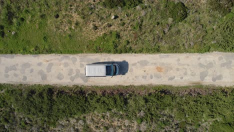 Top-down-drone-view-following-rental-motorhome-along-small-rocky-road