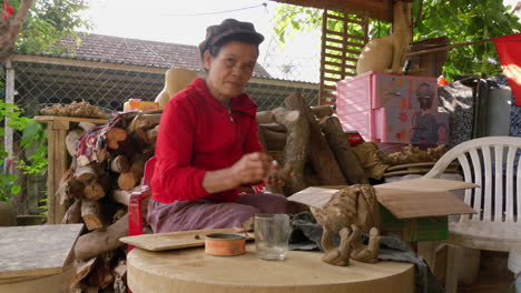 An-old-Asian-lady-skillfully-handcrafts-animal-shaped-clay-flutes,-showcasing-traditional-craftsmanship-and-cultural-heritage