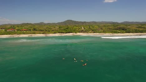 Vista-De-Drones-De-Surfistas-Esperando-En-El-Agua-Por-Olas-Tropicales