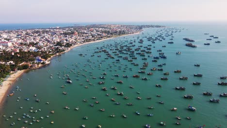 Large-Mui-Ne-fishing-fleet-anchored-along-coastline,-Vietnam