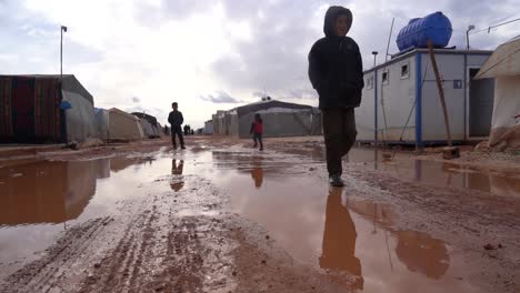 Niños-Sirios-Juegan-En-El-Barro-Fuera-Del-Campo-De-Refugiados,-Muestran-Resiliencia-En-Medio-Del-Desplazamiento