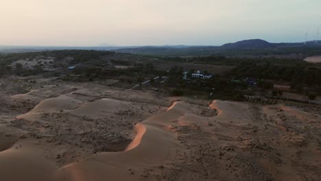Sand-dunes-with-sparse-vegetation-at-sunset-in-Mui-Ne,-Vietnam
