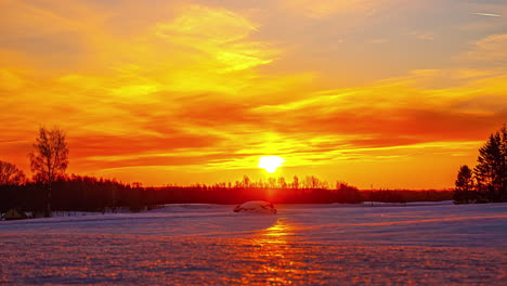 Timelapse-of-bright-sun-rising-in-golden-sky-over-snowy-landscape