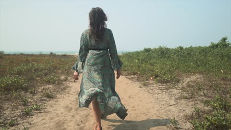 Slow-motion-shot-of-a-beautiful-girl-walking-through-sand-towards-a-sunny-beach