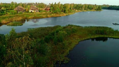 Vacation-homes-in-the-forest-and-on-a-beautiful-lake-in-Latvia,-aerial-rise