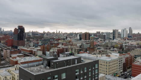 Drone-shot-low-over-buildings-revealing-a-train,-cloudy-evening-in-Upper-Manhattan,-NY