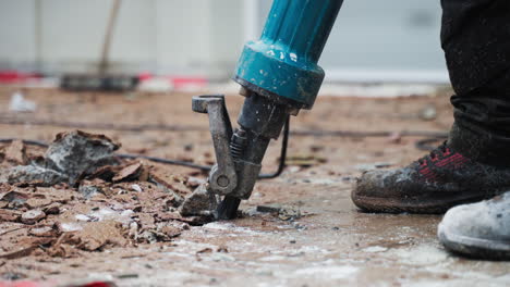 Man-worker-with-jackhammer-machine-destroying-asphalt-or-concrete-road---close-up---reveal-shot