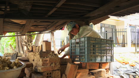 Un-Hombre-En-Thanh-Ha-Coloca-Flautas-De-Arcilla-Con-Forma-De-Animal-Secadas-Al-Sol-En-Un-Horno-De-Leña-Para-Hornear,-Capturando-La-Artesanía-Tradicional-Para-Los-Recuerdos-Turísticos