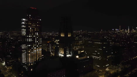 Aerial-view-in-front-of-the-night-lit-Riverside-church,-in-New-York,-USA---descending,-drone-shot