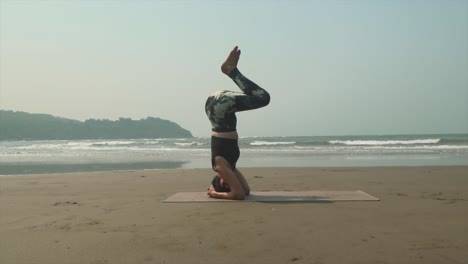Slow-controlled-headstand-teaching-Vinyasa-yoga-class-on-beach-to-students