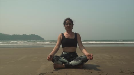 Frauen-Meditieren-Am-Strand-Mit-Nach-Vorne-Geneigtem-Kopf,-Während-Sie-Sich-In-Der-Praxis-Entspannt