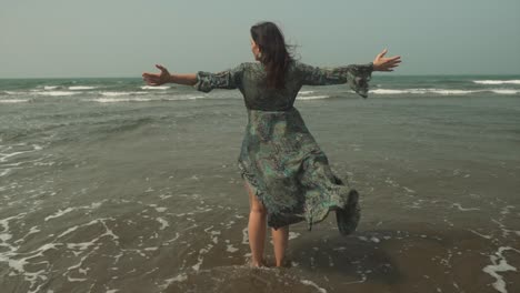 Caucasian-Woman-Stands-With-Open-Arms,-Dress-Blows-in-Ocean-Breeze,-Slowmo