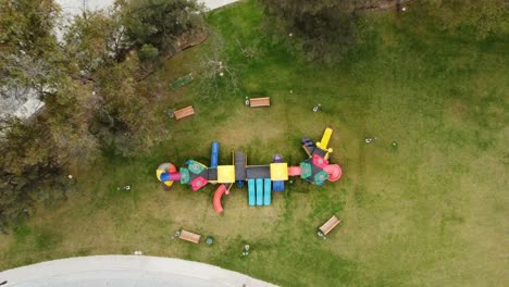 Langsames,-Von-Oben-Nach-Unten-Aufsteigendes-Foto-über-Einem-Farbenfrohen-Kinderspielplatz-Mit-Rutschen