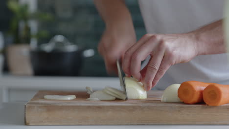 Close-up-of-man-cutting-fresh-onions-with-a-knife-in-a-modern-kitchen