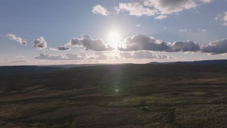 Beautiful-aerial-drone-footage-descending-over-wide,-open-moorland-in-autumn-with-a-low-sun-in-a-blue-sky