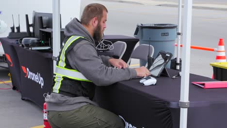 Ein-Drohnenpilot-Durchsucht-Sein-IPad-Und-Sein-Notebook,-Um-Vorab-Die-Vorbereitungen-Für-Einen-Drohnenflug-Zu-Treffen,-Zeitlupe