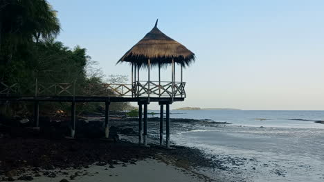 Holzsteg-Mit-Strohschirm,-Am-Strand-Einer-Afrikanischen-Insel,-Bijagós-Archipel-In-Guinea-Bissau,-An-Einem-Tag-Mit-Blauem-Himmel-Und-Ebbe