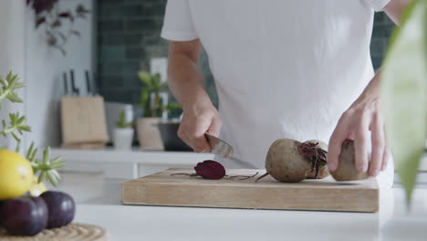 Medium-shot-of-a-man-cutting-fresh-beetroot-with-a-knife-in-a-modern-kitchen