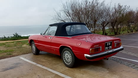 Luxuriöses-Rotes-Alfa-Romeo-Spider-Auto,-Geparkt-In-Einem-Park-Mit-Dem-Meer-Im-Hintergrund