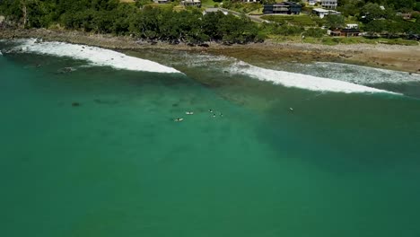 Surfers-patiently-waiting-for-the-next-wave-along-Hot-Water-Beach-in-New-Zealand