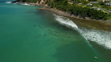 Cinematic-aerial-pan-over-surfers-waiting-to-catch-the-next-break