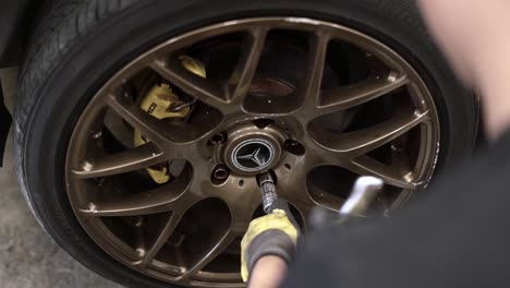 Slow-motion-rotating-shot-of-a-mechanic-removing-the-wheel-bolts-from-a-Mercedes-car