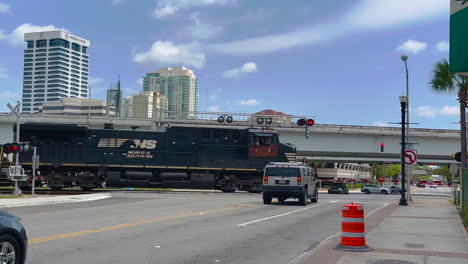 Norfolk-Southern-train-engine-and-cars-travelling-through-city-busy-with-traffic